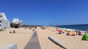 A beach with a wooden walkway leading to the water, umbrellas, and beach chairs. - T1 Avenida Mar 8 200m Praia Wi-fi 4 Pessoas (Loulé)