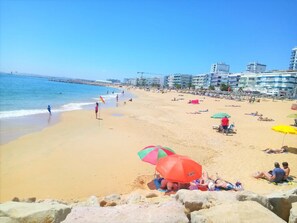 A beach with people sunbathing and swimming, umbrellas, and buildings in the background. - T1 Pontemira 6 - 50M Praia Vista MAR Wi-fi (Loulé)