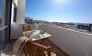 A balcony with a table set for two, overlooking a cityscape and the sea. - T1 Pontemira 6 - 50M Praia Vista MAR Wi-fi (Loulé)