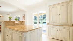 A spacious kitchen with white cabinetry, granite countertops, and a large island.