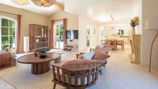 A spacious living area with a round wooden coffee table, cushioned seating, and a television mounted on the wall.
