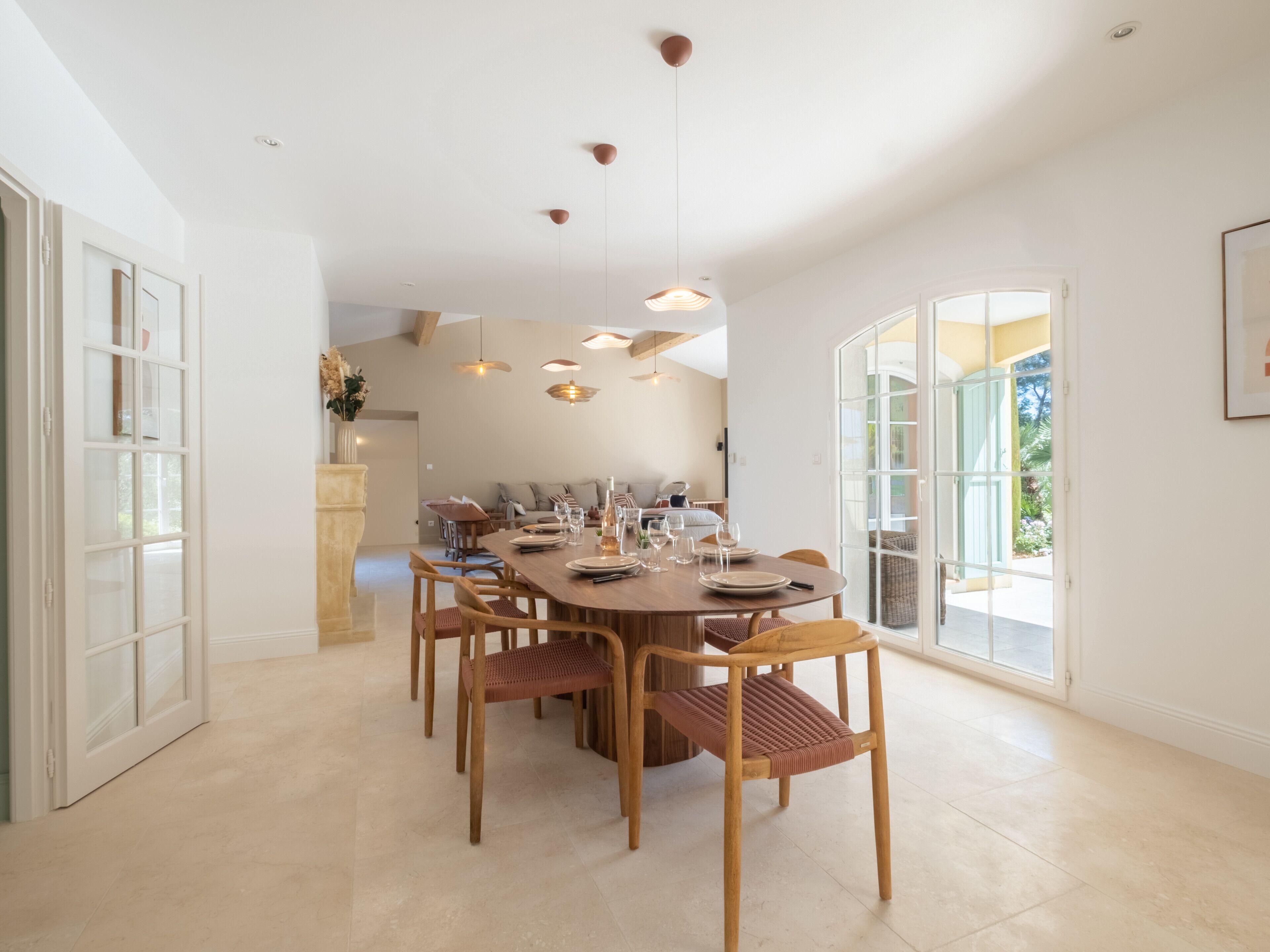 Uma sala de jantar espaçosa com uma grande mesa de madeira, várias cadeiras e iluminação pendente.