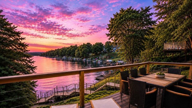 A deck with a view of a lake and sunset, wooden furniture, and a railing. - Your adventure at the Lake. 9 Mi from the Ark Encounter, breathtaking view. (Dry Ridge)