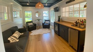 A modern kitchen with a wooden countertop, a built-in dishwasher, and a dining area with a black leather sofa and a white rug. - Spectacular Riverfront Property (Manasquan)