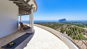 A balcony with a view of the city and sea, a chair, and exercise equipment. - Mirador - By Almarina Villas (Benissa)
