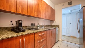 A kitchen with wooden cabinets, granite countertop, stainless steel appliances, and a Breville coffee maker.