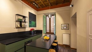 Une cuisine moderne dotée d’un îlot central, de meubles de couleur verte et d’un plafond au style rustique.