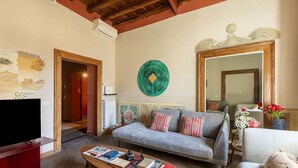 Un salon comprenant un canapé, une table basse avec des livres, un téléviseur et un miroir décoratif.