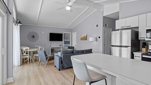 Eine moderne Küche mit weißen Schränken, einem Edelstahlkühlschrank und einem Essbereich mit weißem Tisch und Stühlen.