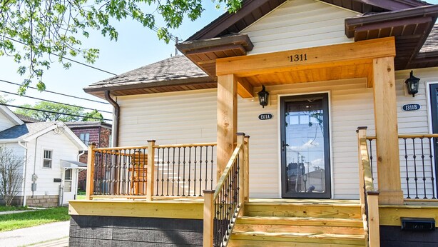 A two-story house with a wooden front porch, a staircase, and a mailbox. - SweetiePie Studio in the Heights-Steps from Everything! (Peoria Heights)