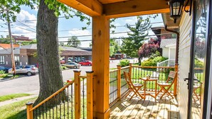 A wooden porch with a railing, a table, and two chairs. - SweetiePie Studio in the Heights-Steps from Everything! (Peoria Heights)