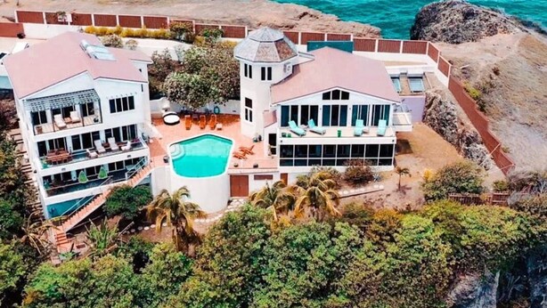 Propiedad frente al mar de dos pisos con piscina, varios balcones y vista al océano.