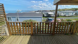 Une terrasse en bois offrant une vue sur un quartier résidentiel, avec des maisons et une voiture garée.