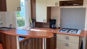 Une cuisine compacte équipée d’une cuisinière à gaz, d’une machine à café et d’une petite fenêtre.