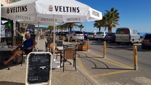 An outdoor café with white umbrellas labeled "VELTINS" and a chalkboard menu. - T1 Pontemira 5 F- A C 50M Praia TV Wifi (Loulé)