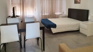 A hotel room with a bed, a desk with a computer, a chair, a bedside table with a lamp, and a painting on the wall. - T0 A C Varandas Mar 3 B Perto Praia Wi-fi (Loulé)
