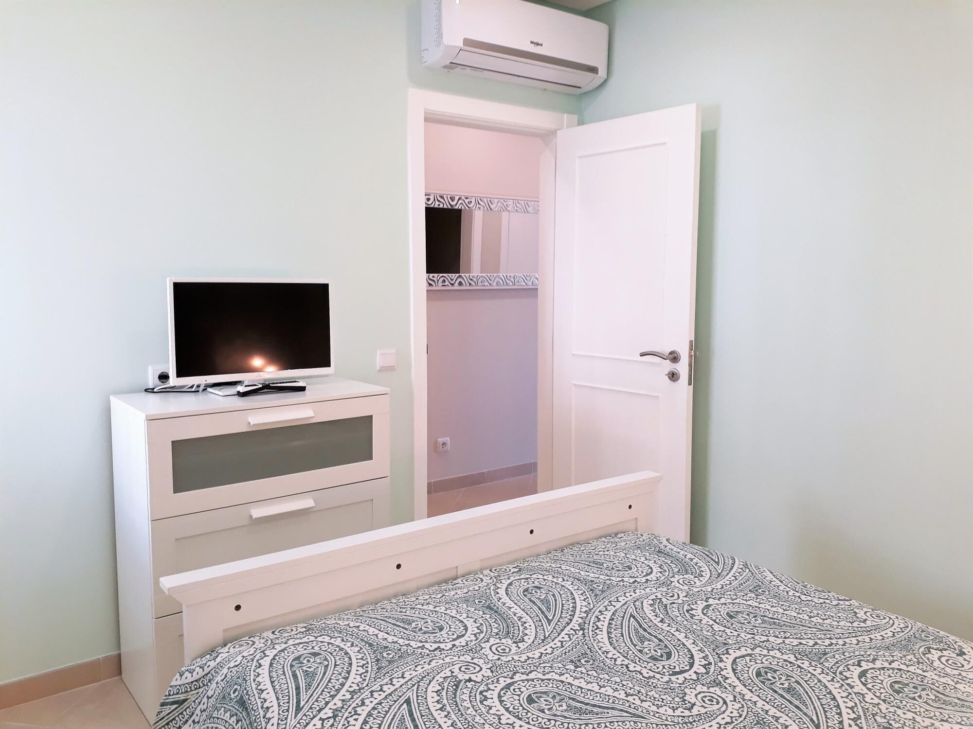 A bedroom with a bed, a TV on a dresser, and a wardrobe.