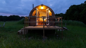 Eine Holzhütte mit einem Balkon, umgeben von Gras.