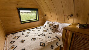 Ein gemütliches Schlafzimmer mit Bett, Fenster und Holz-Kopfteil.
