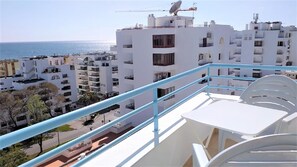 A balcony with a view of a coastal cityscape, featuring modern white buildings and a clear blue sky. - T1 Colina F Rias 8d-a C Garagem Vmar (Loulé)