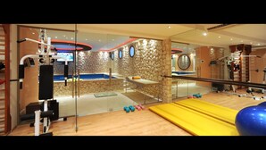 A gym with exercise equipment, a massage table, and a stone wall. - Beautiful 9-Bed Villa in Gouvia with Tennis Court (danilia)