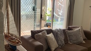 Ein Wohnzimmer mit einem braunen Sofa, einem Modellsegelschiff und einem Blumentopf.