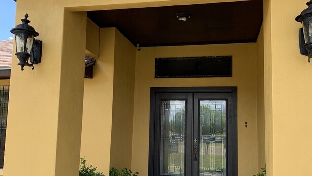 A yellow building with a black door, two potted plants, and a small set of steps leading to the entrance. - Villa Maria home is min from Beach, SpaceX, Downtown Brownsville and Matamos Mex (Brownsville)