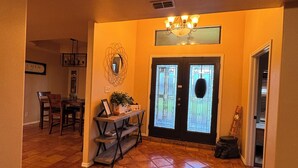 A spacious foyer with a tiled floor, a dining area with a table and chairs, and a double door with a glass panel. - Villa Maria home is min from Beach, SpaceX, Downtown Brownsville and Matamos Mex (Brownsville)