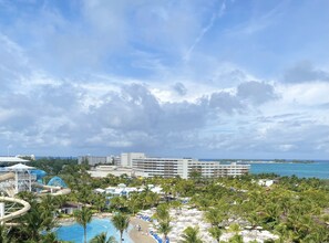 Ein Resort mit einem großen Gebäude, einem Wasserpark und einem Strandbereich mit Sonnenschirmen.