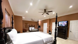 A spacious bedroom with a large bed, a ceiling fan, a television, and a fireplace. - Spacious 3-Bedroom Apartment with WiFi & AC in Lovely Nassau (Nassau)