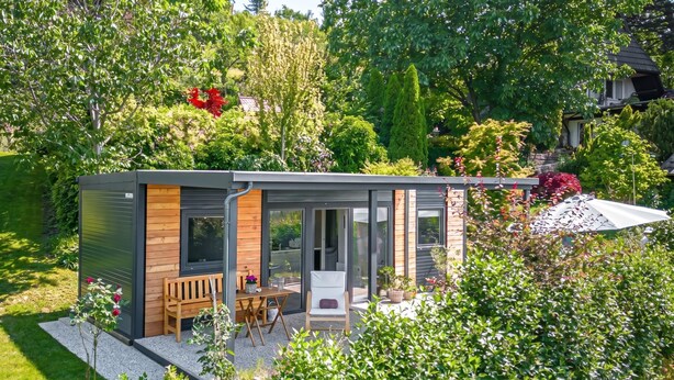 Una casa moderna con un patio, una mesa de madera y sillas.