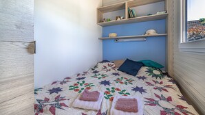 Un dormitorio pequeño y acogedor con una cama, una estantería llena de libros y una ventana.