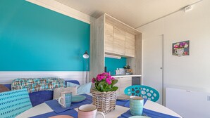 Un comedor con una mesa lista para dos personas, una cesta de mimbre con flores y una pared color turquesa.