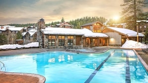 Un complexe hôtelier doté d’une piscine, de bâtiments en pierre et de toits couverts de neige.