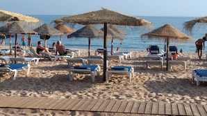 A beach with sun loungers and thatched umbrellas. - T1 Colina Ferias 8C A C Garagem Vista MAR (Loulé)