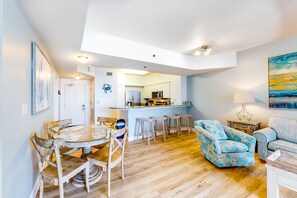 Relax in this open-plan living space with a dining area and comfortable sofa, featuring a modern kitchen and high ceiling.
