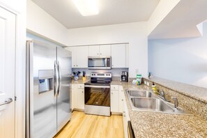 Enjoy cooking in this well-equipped kitchen with a refrigerator, microwave, and oven, set against a clean, minimalist backdrop.