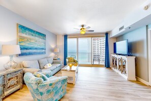 Relax in this stylish living room with a large painting, ceiling fan, and city view from the balcony.