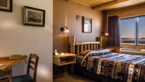 A room with a bed, a desk, and a chair. There are framed pictures on the wall and a window with a view. - Enjoy a lakeview sunset in Room 6 - The Bear's Den - Curriers Lakeview Lodge (Rice Lake)