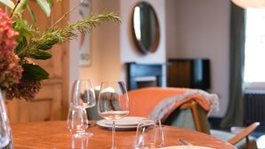 A dining table with four wine glasses and plates, a vase with flowers, and a chair with a blanket.