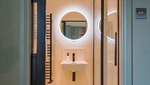 A modern bathroom with a round mirror, a sink, and a towel rack.