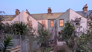 A wooden pathway leading to a house with a garden.