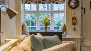 A cozy room with a large window, a vase with flowers, a table, and a bench. - A delightful cottage in the heart of the historic conservation area of Deal (Deal)