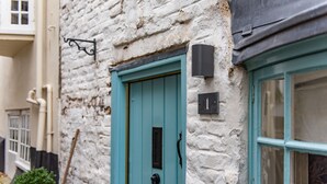 A turquoise door with a black handle, a white brick wall, and a black light fixture. - A delightful cottage in the heart of the historic conservation area of Deal (Deal)