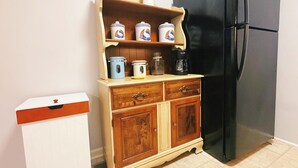 Uma cozinha com armário de madeira, geladeira preta e diversos utensílios sobre o balcão.