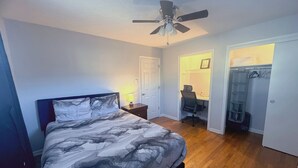 A bedroom with a bed, a desk, and a walk-in closet.