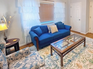 A living room with a blue sofa, a glass coffee table, a patterned rug, and a lamp. - Convenient & Comfortable - Walkable to UK Campus, near Downtown, Keeneland, Rupp (Lexington)
