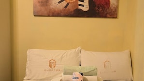 A hotel room with a bed, two pillows with logos, a tray with toiletries, and a painting on the wall. - Jazz Tower A // Cozy Room for 2 Adults //  Best for Short stays (Makati)