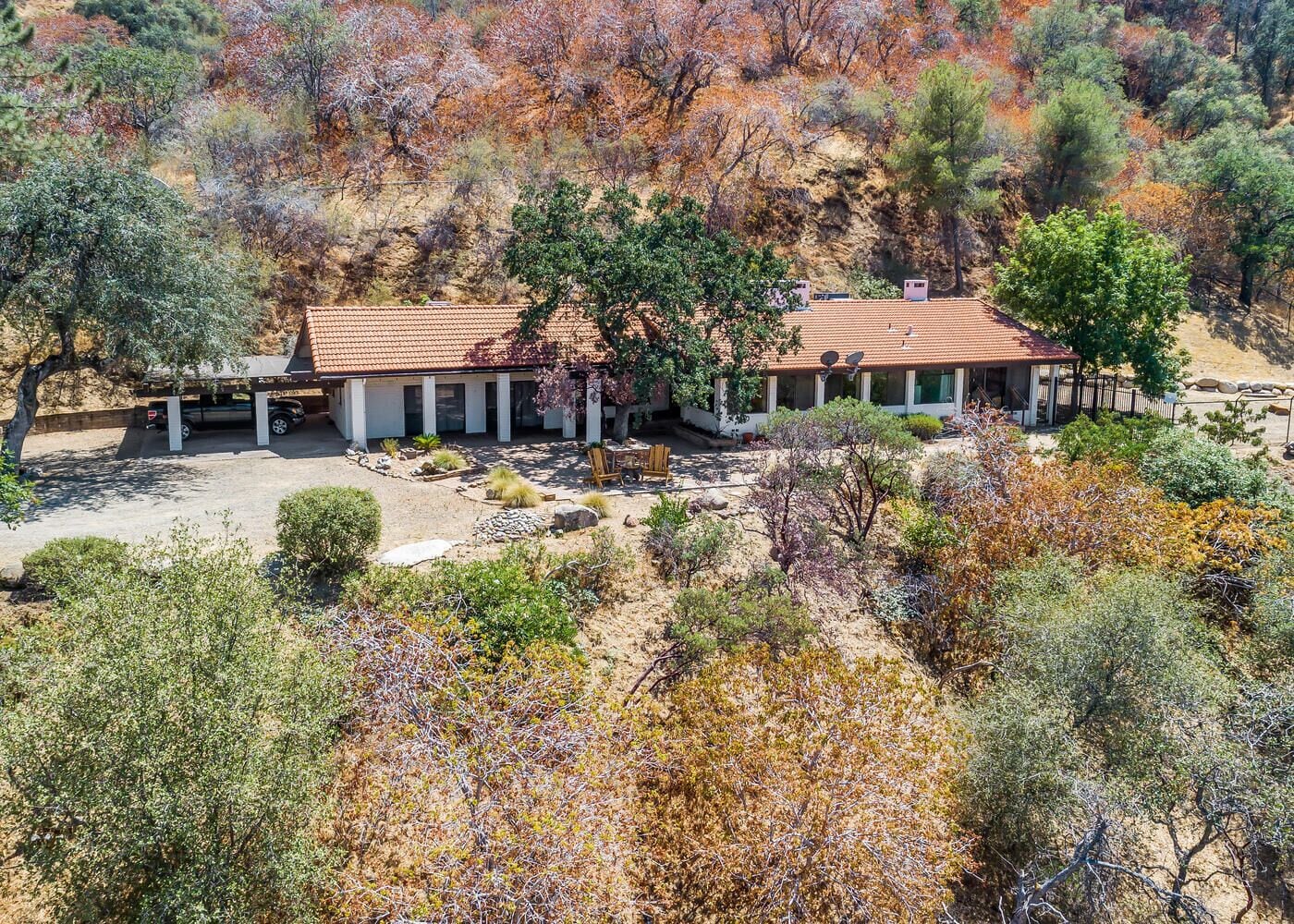 A two-story house with a tiled roof, surrounded by a landscaped garden with various shrubs and trees.