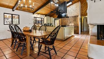 A dining area with a wooden table and chairs, a kitchen with wooden cabinets, and a tiled floor.